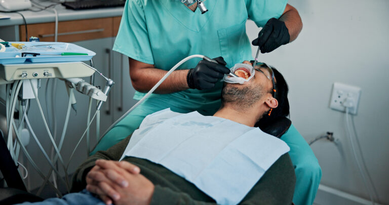 Man, patient and dentist cleaning mouth with tools for bacteria or germ removal at orthodontist. Male person, client or teeth surgeon with suction for tooth extraction, dental or oral care at clinic.