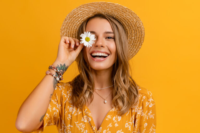 beautiful attractive stylish woman in yellow dress and straw hat holding daisy flower romantic mood posing on yellow background isolated in love summer fashion trend style, natural look