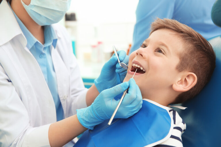 Dentist examining little boy's teeth in clinic