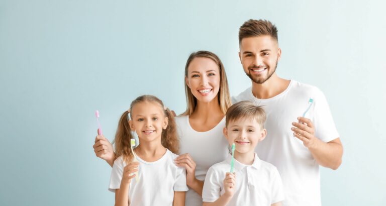 Portrait of family with toothbrushes on light background