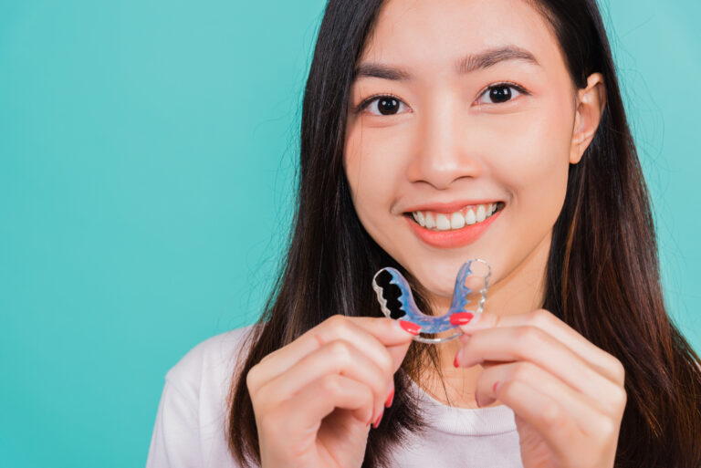 Teeth retaining tools after removable braces, Portrait young Asian beautiful woman smiling holding silicone orthodontic retainers for teeth, Orthodontics dental healthy care concept