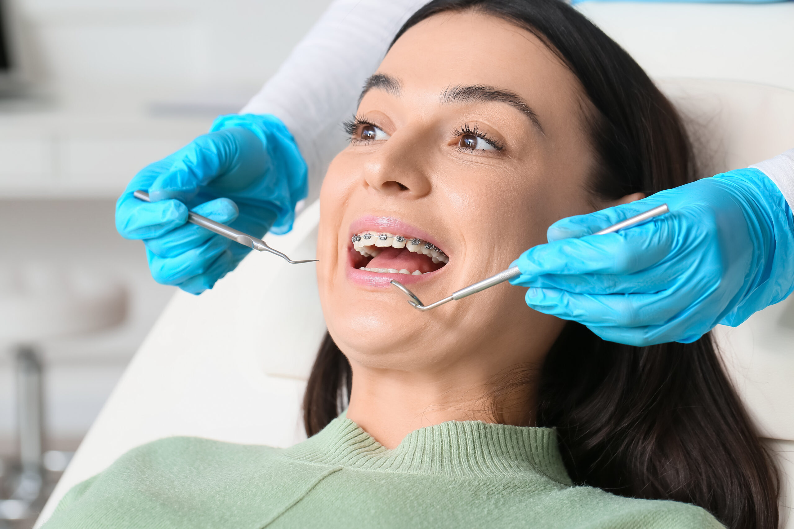 Beautiful woman with dental braces visiting dentist in clinic