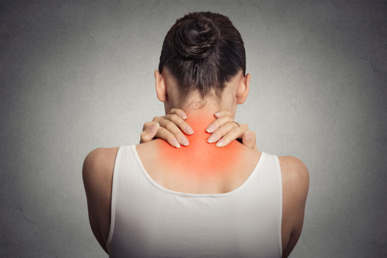 Healthy lifestyle. Back and spine disease. Closeup back view tired female massaging her neck colored in red isolated on gray background
